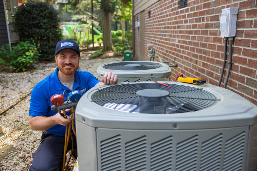 Technician servicing two AC condenser units